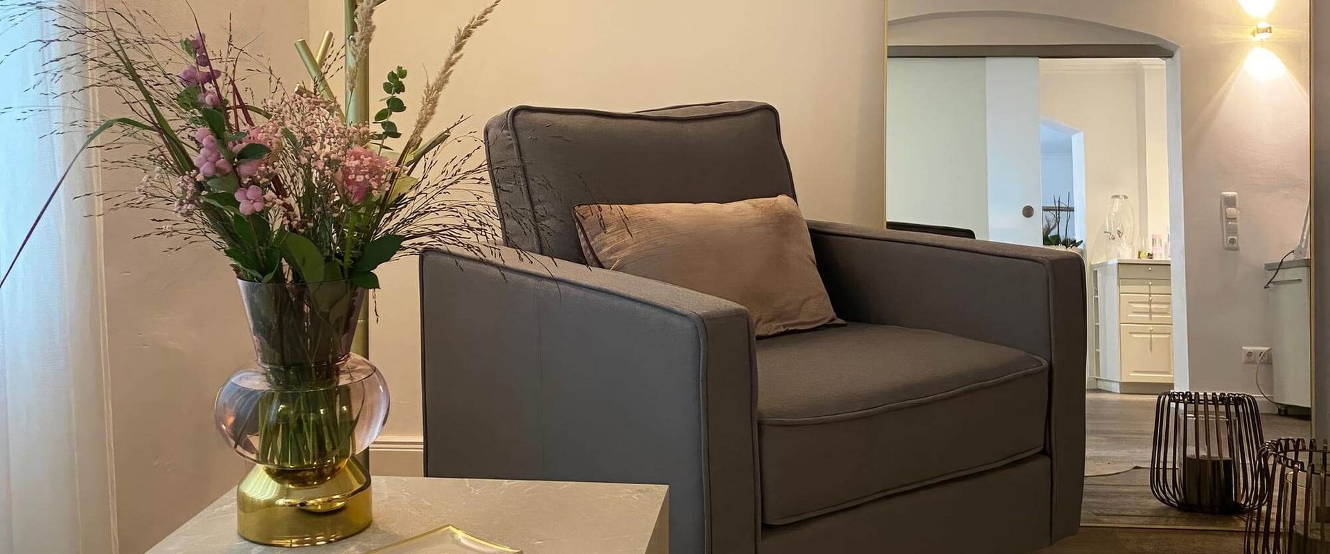 Ein stilvolles Kosmetikstudio mit einem gemütlichen Sessel und frischen Blumenarrangements lädt zur Entspannung ein.