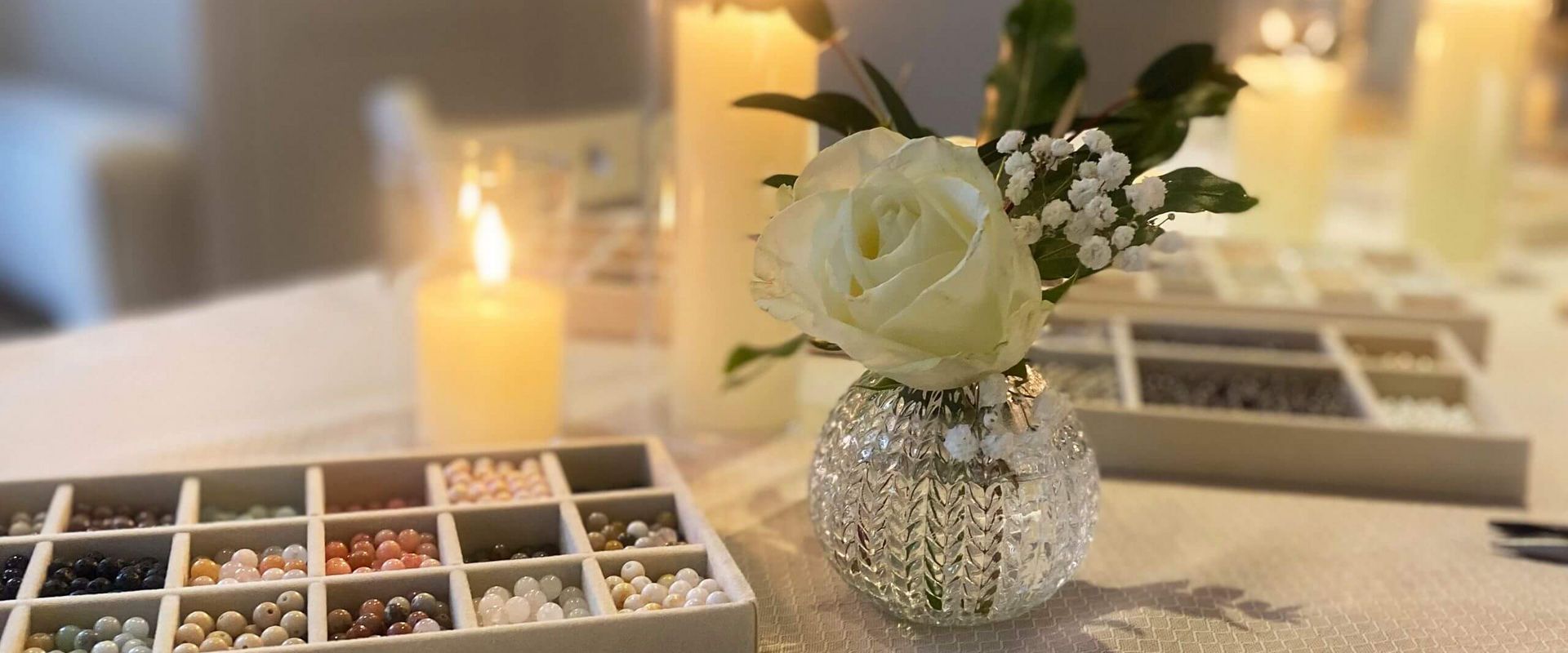 Ein schön dekorierter Tisch im Kosmetikstudio zeigt eine Blumenvase, Kerzen und eine Auswahl an Perlen für ein Babor-Workshop.