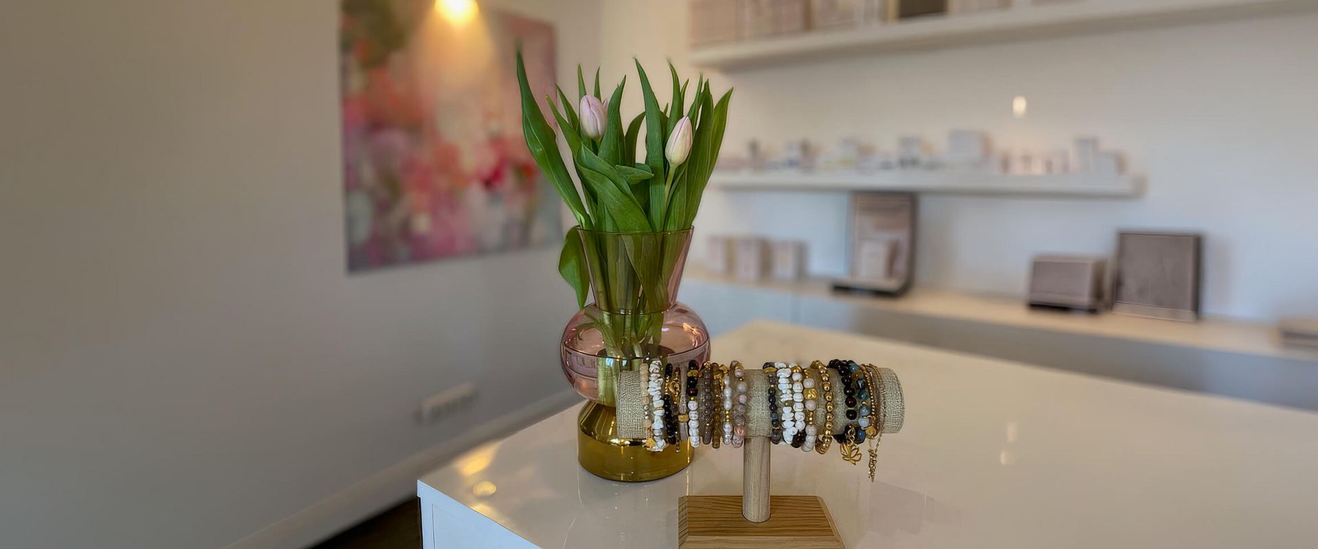 Ein stilvolles Kosmetikstudio präsentiert eine elegante Vitrine mit Schmuck und frischen Tulpen in einer modernen Atmosphäre.