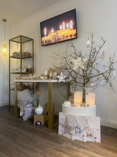 Ein stilvoll dekoriertes Kosmetikstudio mit Kerzen und einem festlichen Baum lädt zur Entspannung ein.