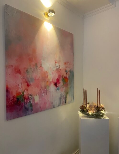 Ein hell erleuchtetes Kosmetikstudio zeigt ein abstraktes, rosa Kunstwerk neben einer festlichen Kerzendekoration.