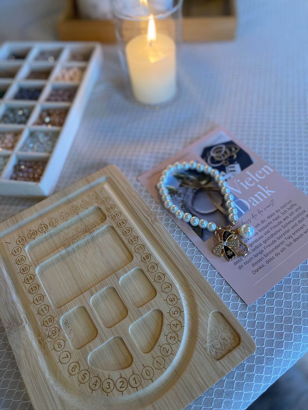 Ein stilvolles Kosmetikstudio zeigt eine Holzplatte mit Schmuckdesign, umgeben von Perlen und einem warmen Kerzenlicht.