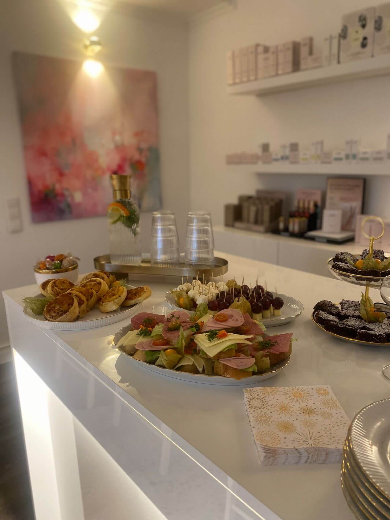 Ein eleganter Empfangstisch im Kosmetikstudio bietet eine Auswahl an feinen Snacks und Getränken für die Gäste.