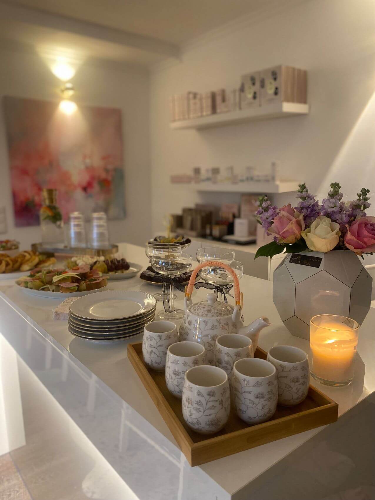 Ein elegantes Kosmetikstudio zeigt eine stilvolle Teepause mit köstlichen Snacks, Babor-Produkten und frischen Blumen.