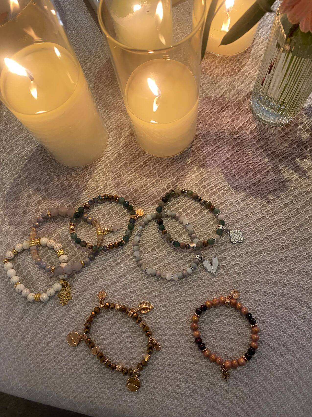 Auf einem eleganten Tisch liegen verschiedene armbänder zwischen brennenden Kerzen, ideal für ein entspannendes Kosmetikstudio | © Babor.